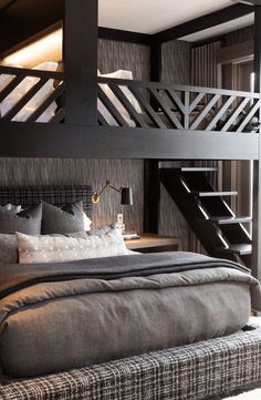 a large bed sitting under a wooden staircase next to a wall mounted light above it