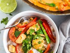 a white bowl filled with rice and veggies next to a lime wedge on the side