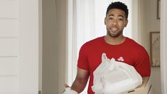 a man in a red shirt is holding a box full of white bags and gloves