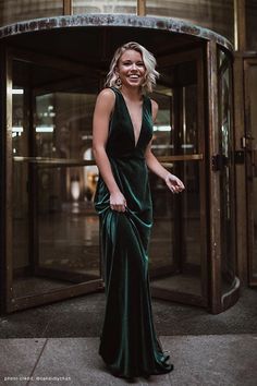 a woman standing in front of an entrance wearing a green dress