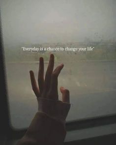 someone holding their hand up in front of a window that says, everyday is a chance to change your life