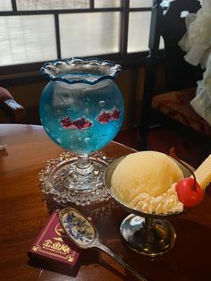 an ice cream sundae sits on a table next to a book and spoons