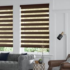 a living room with two windows covered in shades of brown and white striped blindes