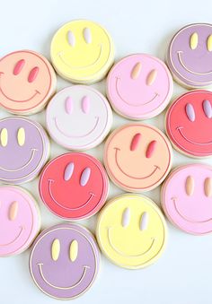 colorful cookies decorated with smiley faces are arranged in the shape of a circle on a white surface