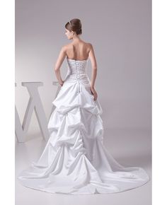 a woman in a white wedding dress is posing for the camera with her back to the camera