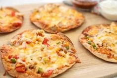 small pizzas with cheese and vegetables on a cutting board