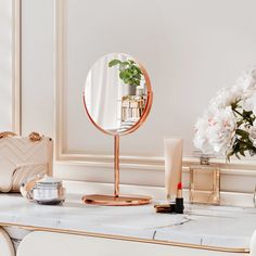 a vanity with a mirror, vase and cosmetics on it