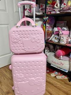 two pink suitcases sitting on the floor in front of a closet full of toys