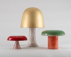 three different colored mushrooms sitting next to each other on a white surface with a gold dome