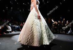 a model walks down the runway in a white gown