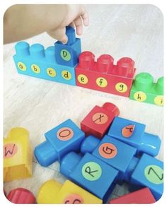 a child's hand is playing with blocks and letters