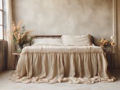 a bed sitting in a bedroom next to a window with flowers on top of it