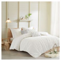 a bed with white comforter and pillows in a room