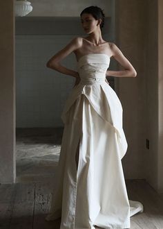 a woman in a white dress standing on a wooden floor with her hands on her hips