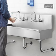 a man standing in front of a sink with two faucets on the wall