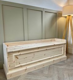 a large wooden box sitting on top of a hard wood floor next to a lamp