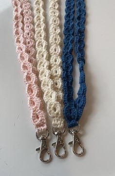 three crocheted lanyards with metal clasps on each side, one blue and one pink