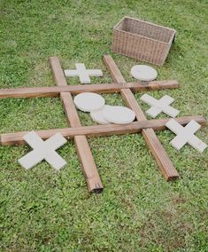 wooden crosses laid out on the grass with bowls and baskets in the backgroud