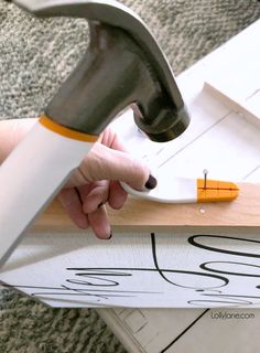 a person using a hammer to cut out the letters on a piece of wood that is being used as a sign