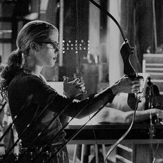 black and white photograph of a woman aiming an arrow at something in the air with her hands