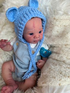 a baby wearing a blue bear hat on top of a white blanket