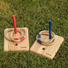 two wooden coasters with ropes on them sitting in the grass, one has a red and blue umbrella