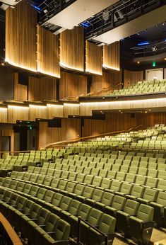 an empty auditorium with rows of green seats and wooden partitions on the wall above