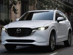 a white mazda cx - 5 driving down the street