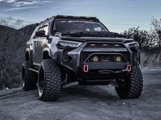 the front end of a black four - doored suv parked on a dirt road