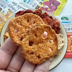 a person holding up a fried item on a plate with other food items in the background