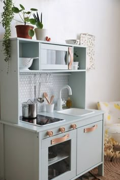 a toy kitchen with pots and pans on the stove top, sink and cabinets