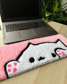 an open laptop computer sitting on top of a wooden table next to a pink rug