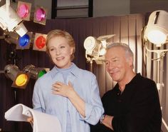 a man and woman standing next to each other in front of some colorful light bulbs