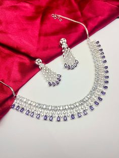 Gorgeous fine quality faux Purple color stone with CZ stones  studded in white gold rhodium plating with CZ high quality stones Comes with matching earrings. AAA quality cubic zirconia used. Highest quality and craftsmanship Necklace Fitting is adjustable comes with silver plated back metal chain Earrings Closure: Pushback Necklace Closure: Hook Cubic Zirconia Jewelry Sets With Stone Setting For Party, Silver Cubic Zirconia Jewelry Sets With Stone Setting, Cubic Zirconia Jewelry Sets With Stone Setting, Celebration Jewelry Sets With Cubic Zirconia Stone Setting, Round Cubic Zirconia Jewelry Sets With Stone Setting, Silver American Diamond Jewelry Sets With Stone Setting, Dazzling Crystal Jewelry Set With Stone Setting, Silver Jewelry Sets With Stones For Celebration, Dazzling Silver Bridal Necklace With Stone Setting