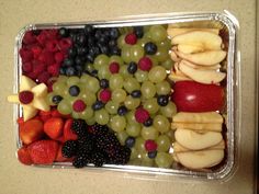 a plastic container filled with grapes, strawberries, and apples in the shape of a christmas tree