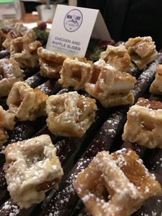 there are many different desserts on the tray for sale at this store, including donuts and waffles