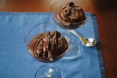 two glasses filled with chocolate ice cream on top of a blue napkin