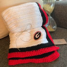 a crocheted blanket sitting on top of a couch next to a glass vase