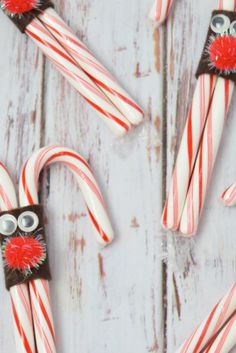 some candy canes with googly eyes are on a white wooden table and one is decorated like an owl