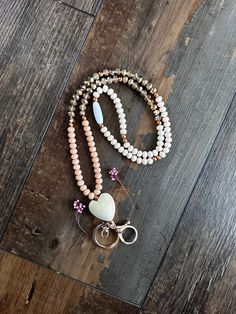 two bracelets with beads and charms on top of a wooden floor next to a keychain