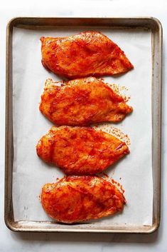 three pieces of chicken sitting on top of a pan