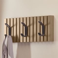 there is a coat rack with three coats hanging on it and a towel hanger next to it