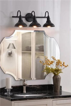 a bathroom vanity with a mirror and two lights on top of it, next to a vase with flowers