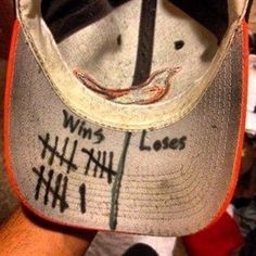 a person wearing a hat with writing on the front and side of it, that says win's losing