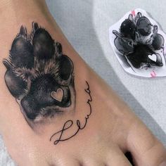 a tattoo on the foot of a person with a dog paw and name below it