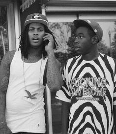 two young men standing next to each other while talking on cell phones in front of a store