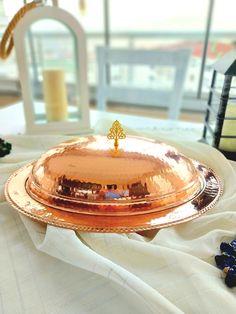 a gold platter sitting on top of a table next to a white table cloth