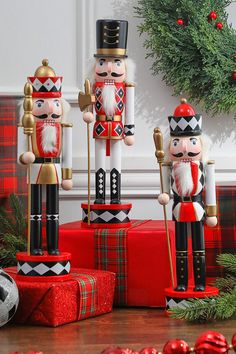 three wooden nutcrackers sitting next to christmas presents