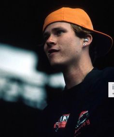 a young man wearing an orange hat and ear piercings