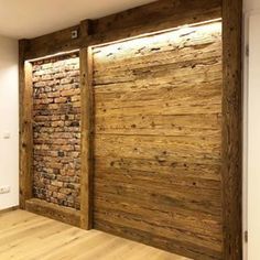 an empty room with wooden doors and brick wall behind the door is a wood floor